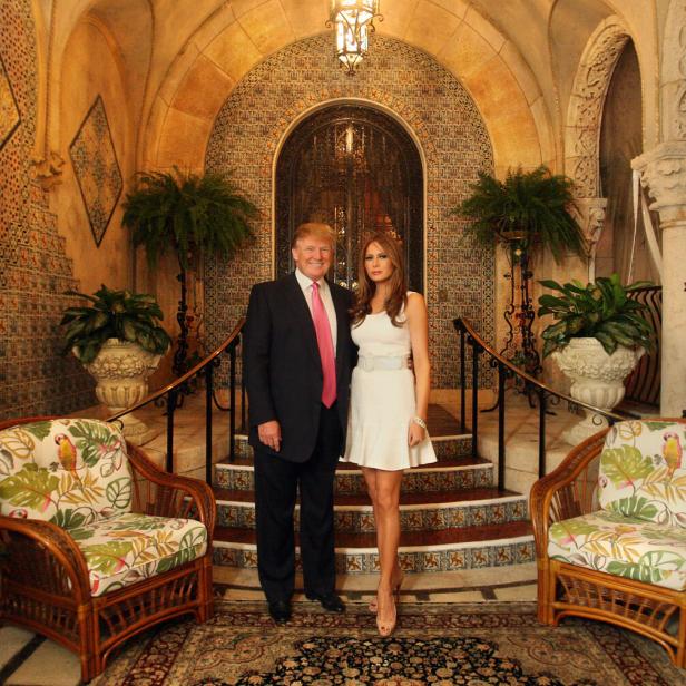 Trump und seine Frau stehen auf einem Teppich vor einer mit Fliesen gekachelten Stufe. Der Türbogen im Hintergrund und die Mauer wirken spanisch-maurisch.