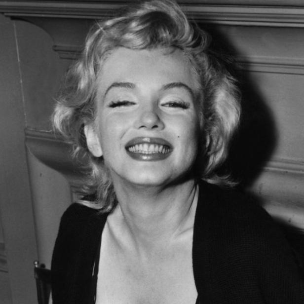 Marilyn Monroe lächelt in einem Schwarzweißporträt.