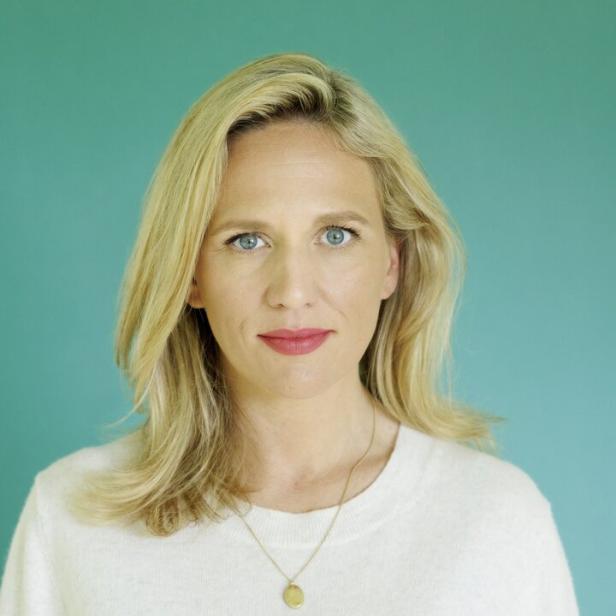 Porträt einer blonden Frau mit blaugrünem Hintergrund.