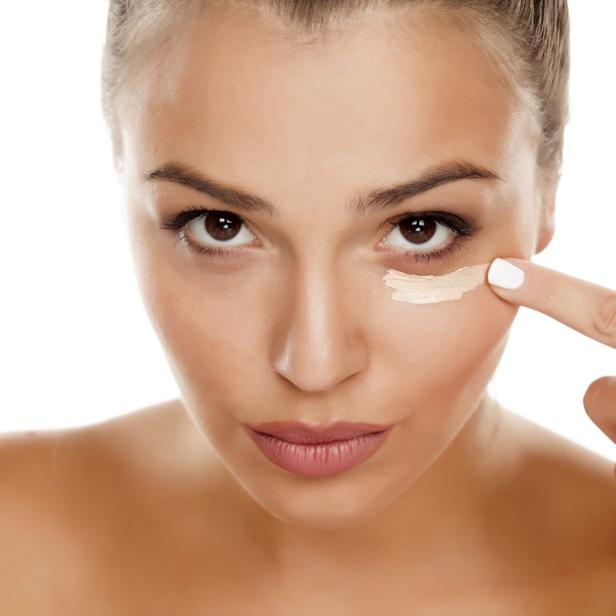 Frau trägt Concealer auf.