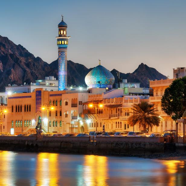 Blick auf Maskat, Oman, mit Moschee und Bergen im Hintergrund.