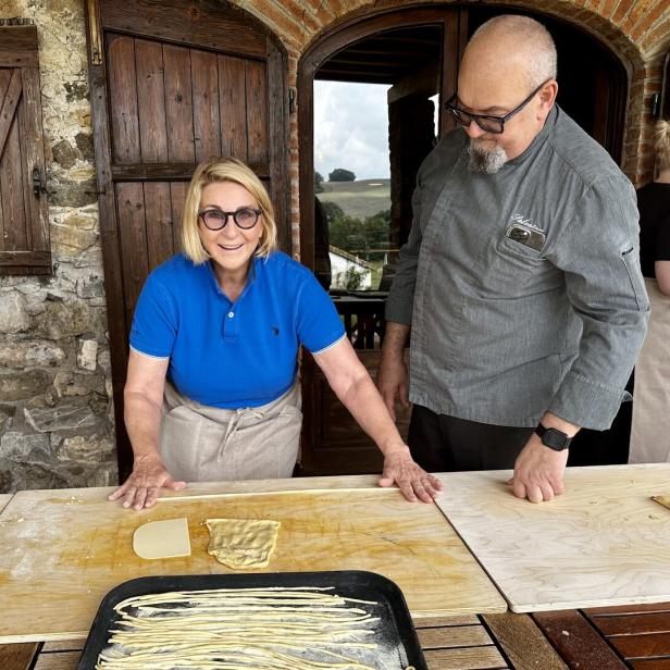 Eine Frau und ein Koch bereiten zusammen Pasta in einer Küche zu.