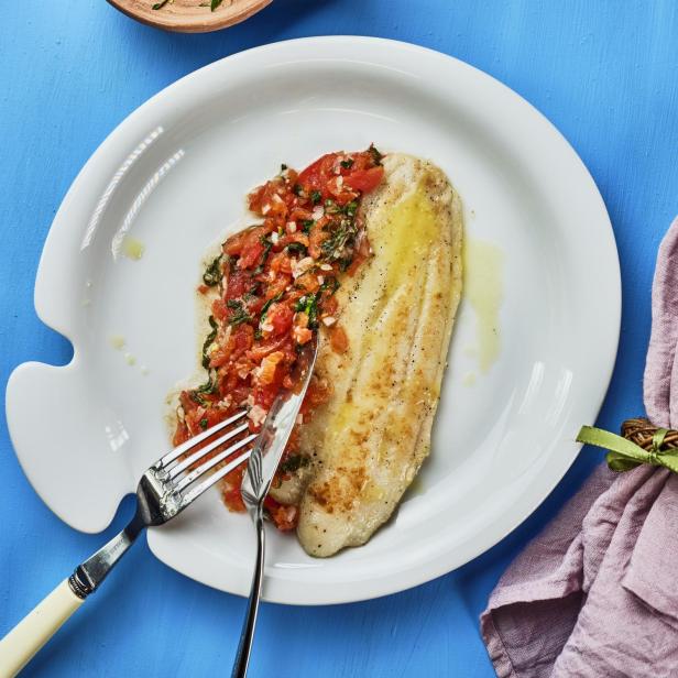 Gebratenes Fischfilet mit Tomaten-Kräuter-Sauce auf einem Teller.