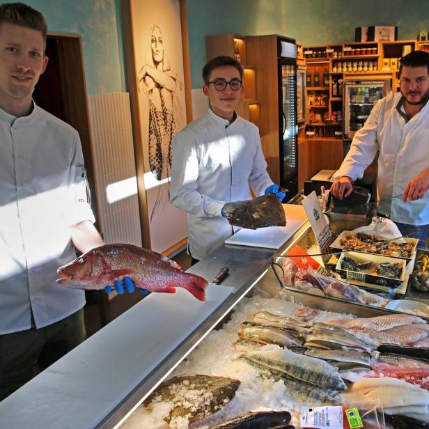 Drei Mitarbeiter präsentieren frischen Fisch in einem Geschäft namens „Lieblingsfisch“ im 2. Bezirk in Wien.