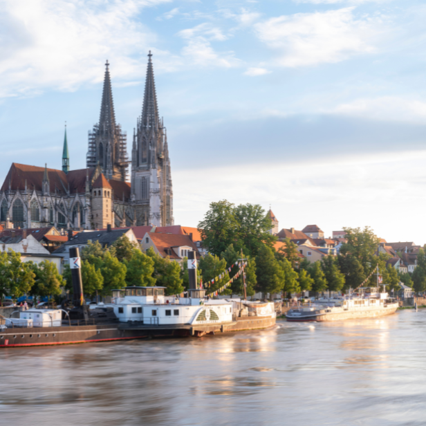 Blick auf die Stadt Regensburg, Deutschland, mit Schiffen, die auf der Donau fahren, umgeben von historischen Gebäuden.