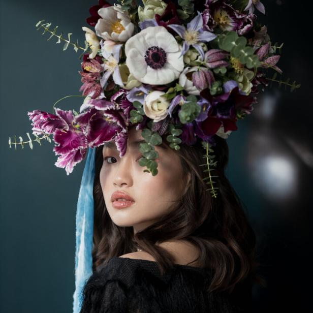 Eine Frau mit einem großen Blumenkopfschmuck aus weißen und violetten Blumen.