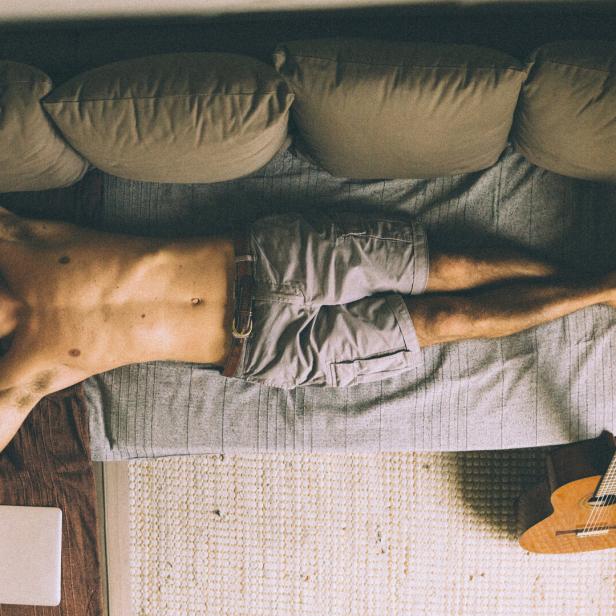 Junger Mann liegt entspannt auf Sofa