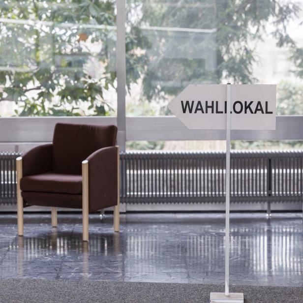 Zwei leere Sessel stehen in einem Wahllokal.