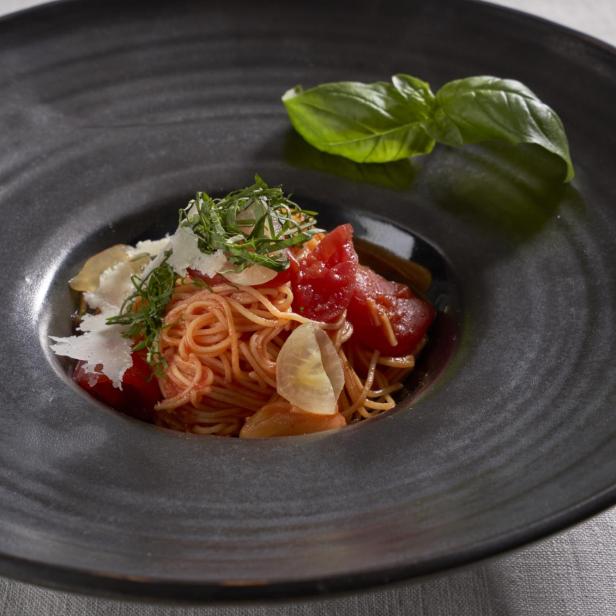 Ein Teller Engelshaar-Pasta mit Tomaten, Basilikum, Knoblauch und Käse.