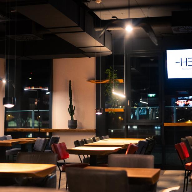 Innenansicht des Restaurants „Heat“ mit Tischen und Stühlen.