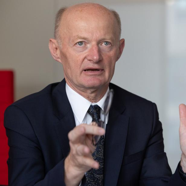 Ein Mann im Anzug gestikuliert während eines Gesprächs.