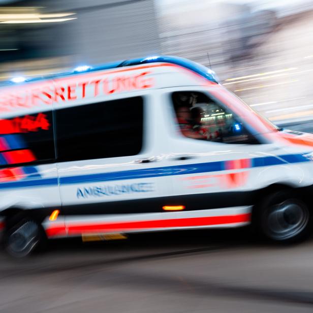 Eine weiße Ambulanz mit Blaulicht fährt schnell durch die Stadt.