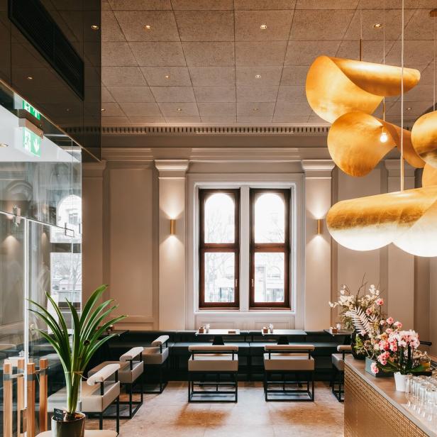 Innenansicht eines eleganten Restaurants mit goldenen Lampen und stilvoller Einrichtung.