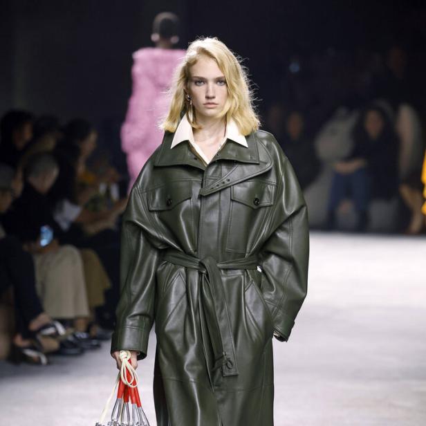 Eine Frau trägt einen olivgrünen Ledermantel von Bottega Veneta auf dem Laufsteg.