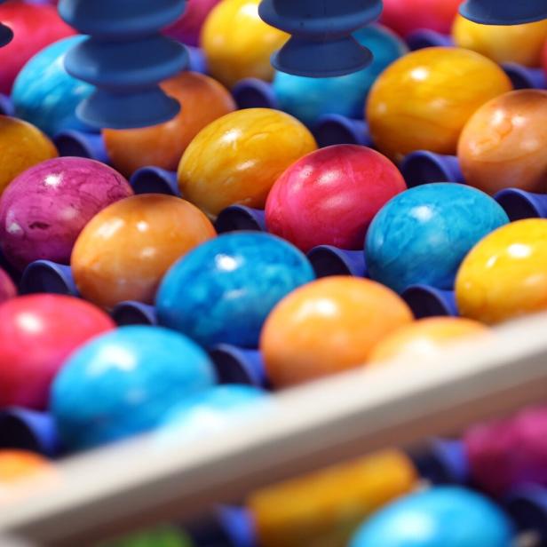 Bunte Ostereier liegen in einer Sortiermaschine.