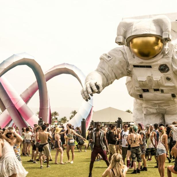 Coachella: Zahlreiche Festival-Besucher sammeln sich auf einer Wiese vor einer riesigen Astronauten-Statue.