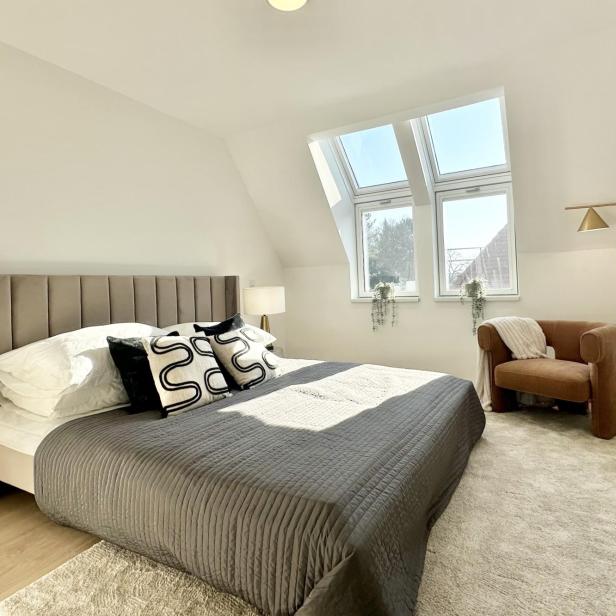 Schlafzimmer mit einem Bett, einem Stuhl und einem Fenster, das Tageslicht hereinlässt.