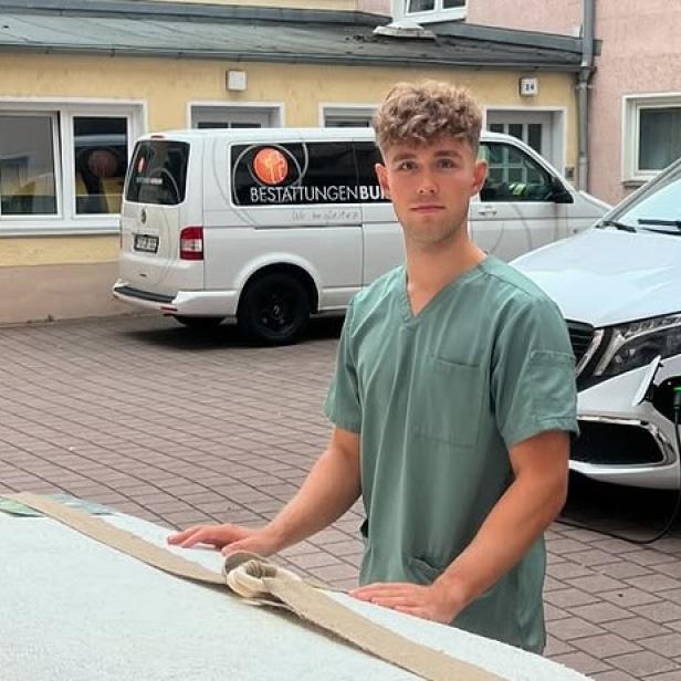 Bestatter Luis Bauer steht vor einem weißen Sarg