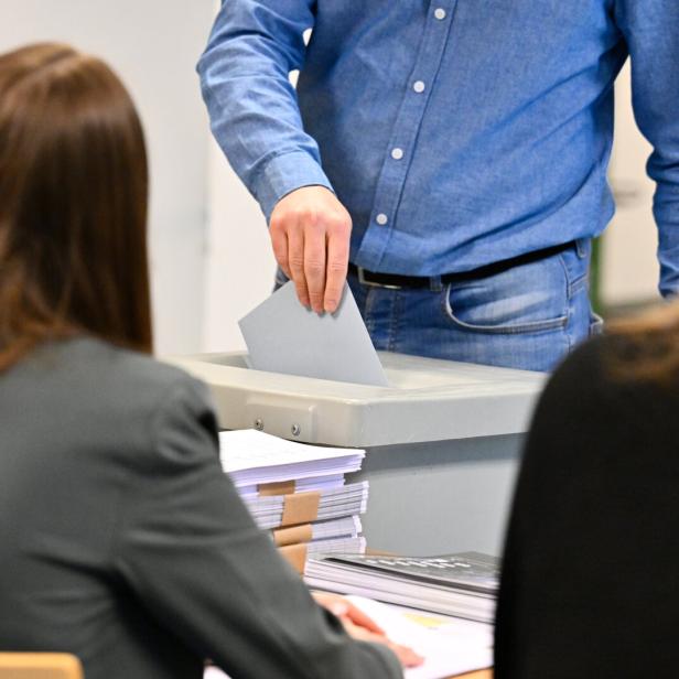 Eine Person wirft einen Stimmzettel in eine Wahlurne.