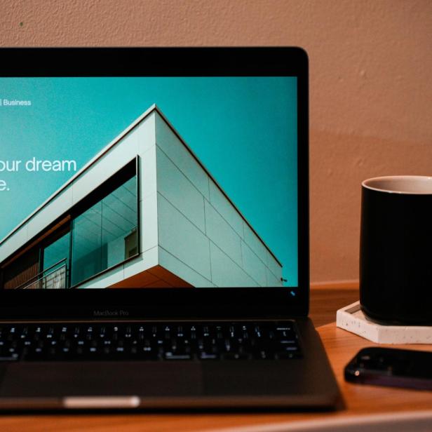 Der Bildschirm eines Laptops, daneben steht eine Tasse. 