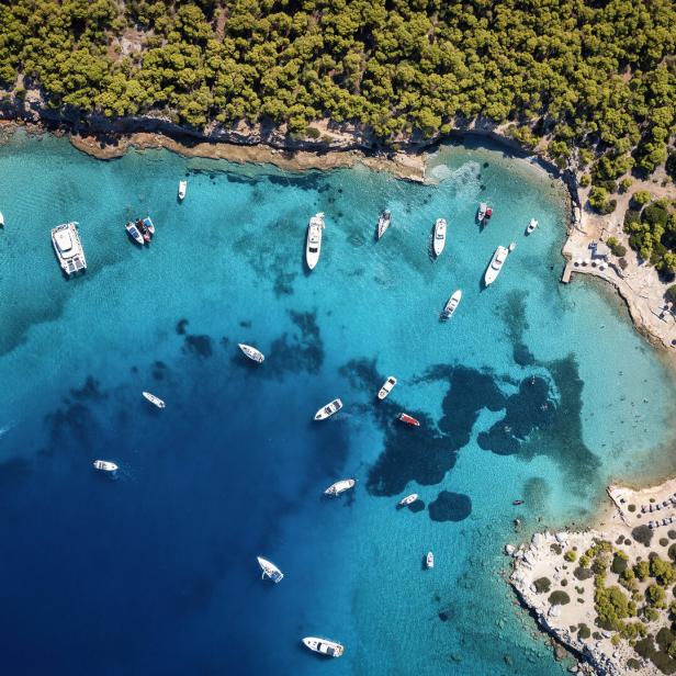 Luftaufnahme einer Bucht mit türkisfarbenem Wasser und mehreren Booten.