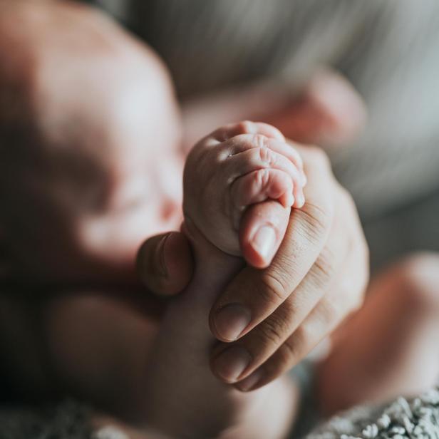 Frauenhand hält kleine Babyhand