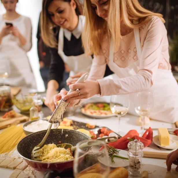 Eine Gruppe von Frauen bereitet gemeinsam eine Mahlzeit in einer Küche zu.