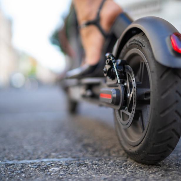 Nahaufnahme vom Hinterrad eines Elektrorollers auf einer Straße.