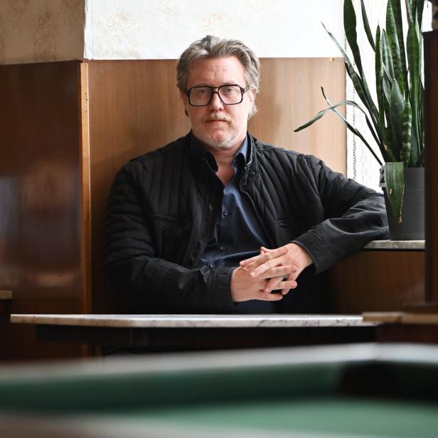 Ein Mann mit Brille sitzt an einem Tisch in einem Café.