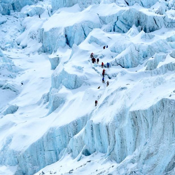 Eine Gruppe von Bergsteigern auf einem schneebedeckten Gletscher im Himalaya.