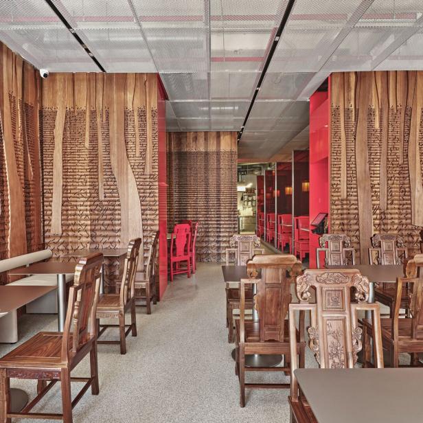 Innenansicht eines Restaurants mit Holzwänden und geschnitzten Stühlen.