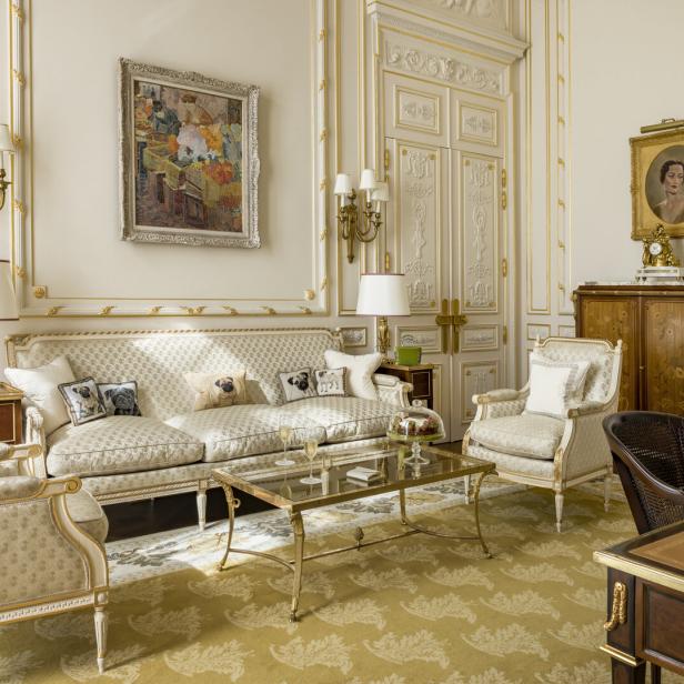 Ein elegant eingerichtetes Wohnzimmer mit goldenen Akzenten und Gemälden an den Wänden.