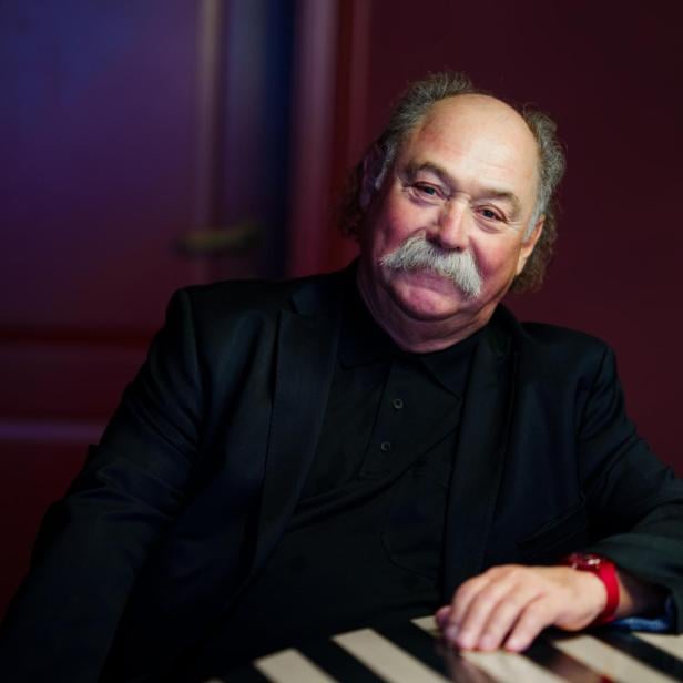 Michael Musalek sitzt an einem Tisch mit schwarz-weißem Muster.