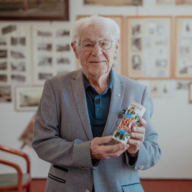 Ein Mann steht vor einer Wand mit schwarz-weiß Bildern