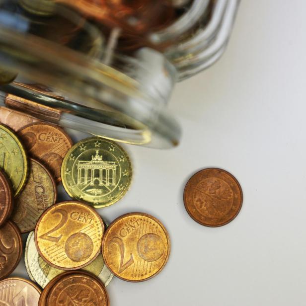 Auf dem Bild sieht man einen umgelegten Glasbehälter aus dem einige Euro- und Centmünzen herausfallen