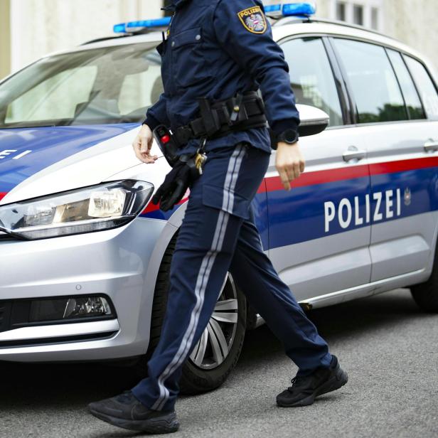 Ein Polizist geht an einem Polizeiauto vorbei.