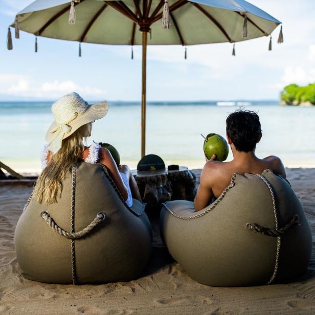 Ein Paar entspannt in Sitzsäcken am Strand mit Blick auf das Meer.