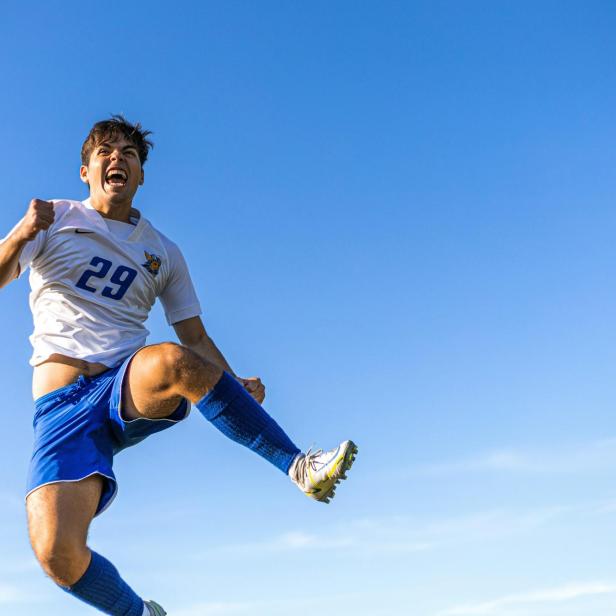 Ein Fußballspieler springt in die Luft vor Freude. 