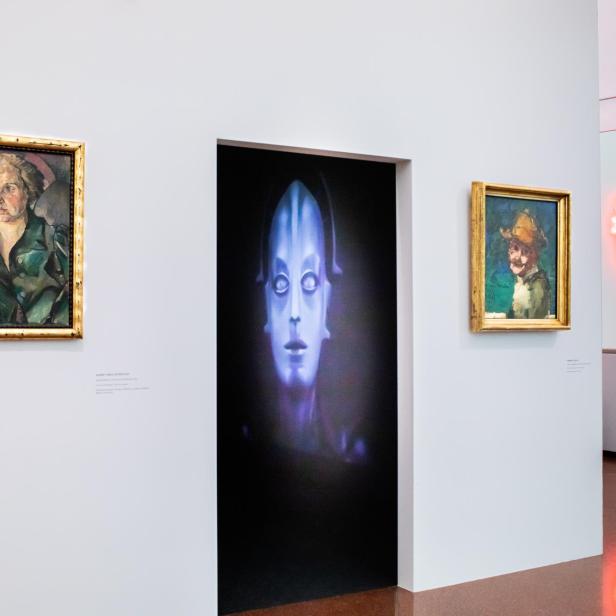  Ein Ausstellungsraum mit Bildern, Filmausschnitten und Kunstwerken.