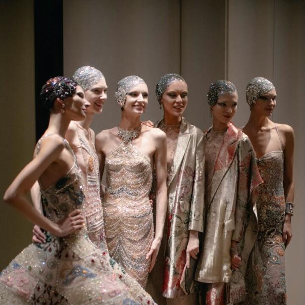 Eine Gruppe von Frauen in glitzernden Kleidern und Kopfbedeckungen posiert für ein Foto.