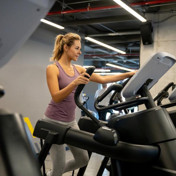 Eine Frau trainiert im Fitnessstudio auf einem Crosstrainer.