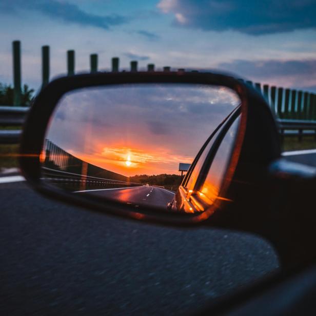Im Seitenspiegel eines Autos ist der Sonnenuntergang zu sehen