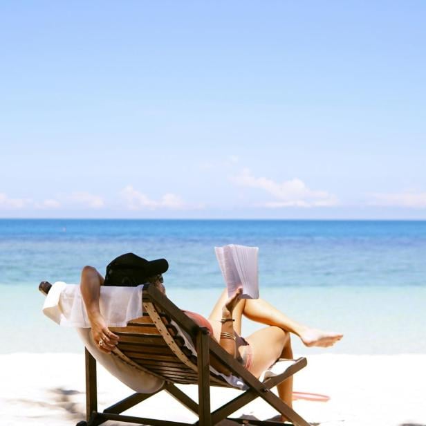 Eine Frau liest an einem Strand ein Buch 