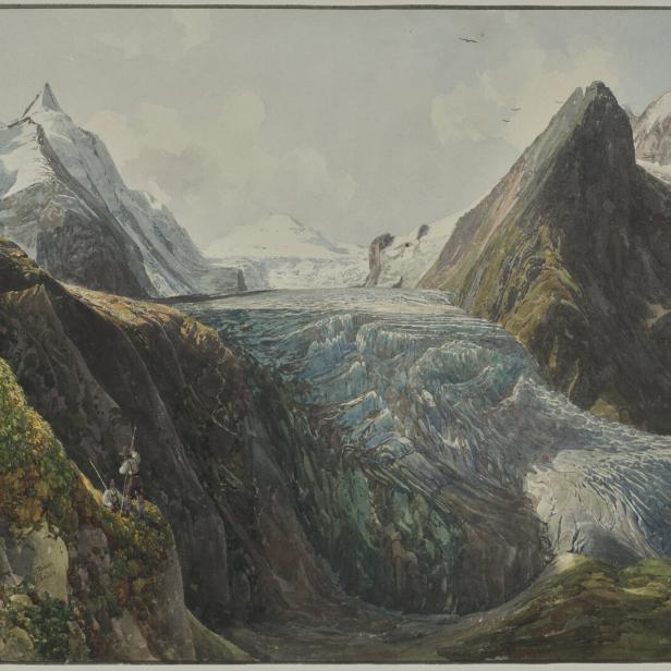 Ein Gletscher erstreckt sich zwischen hohen Bergen, während drei Personen am Rande einer Klippe stehen.