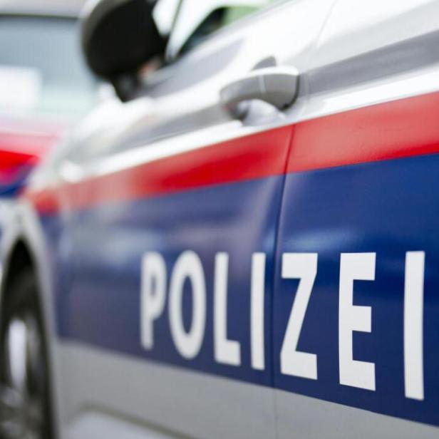 Zwei österreichische Polizeiautos mit blau-rotem Streifen und dem Wort „Polizei“ nebeneinander geparkt.