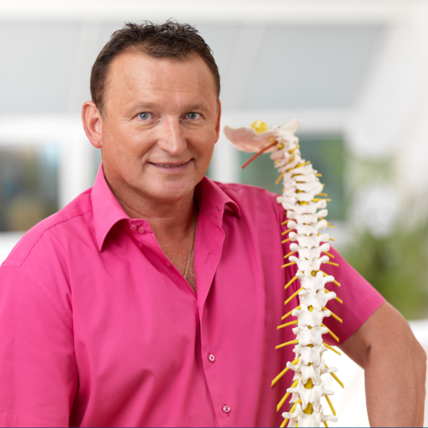 Ein Mann in einem pinken Hemd mit einem Rückenmarkknochen im Arm. 