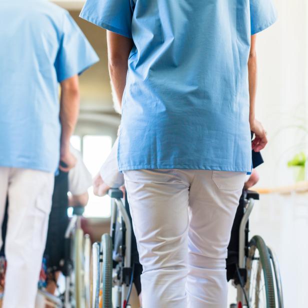 Midsection Of Nurses Pushing Wheelchairs