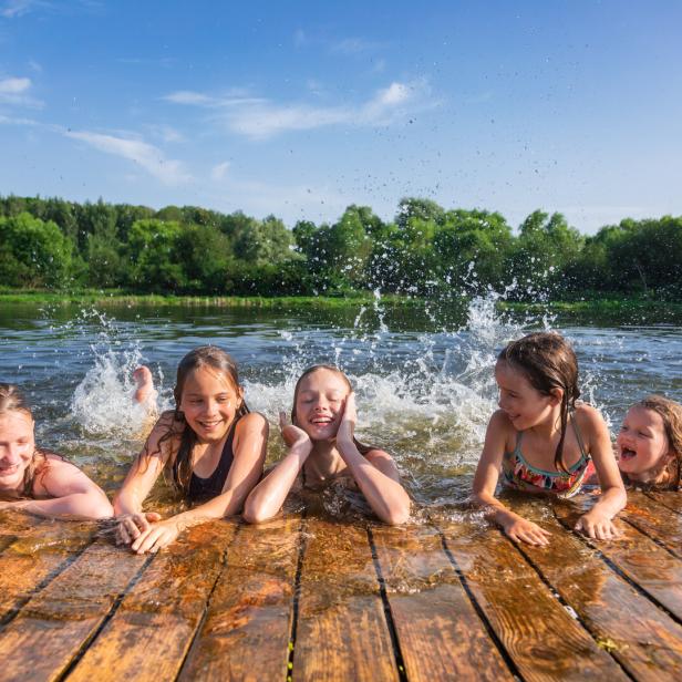Fröhliche Kinder genießen die Sommerferien an einem See.