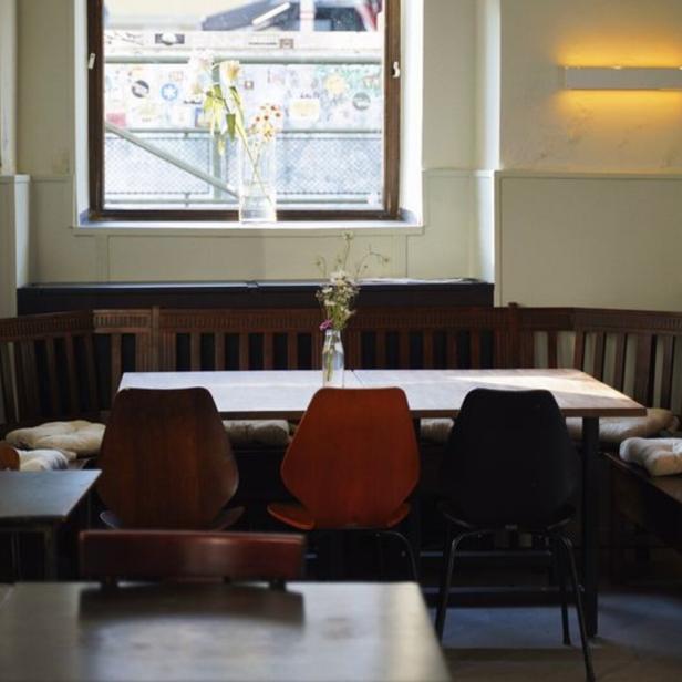 Ein Innenraum mit Holzbänken, Stühlen und Tischen in einem Restaurant.