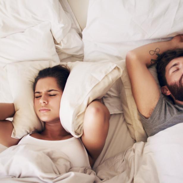 Mann schnarcht im Bett.